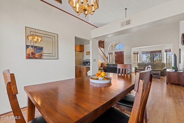 dining area featuring light wood-style floors, visible vents, stairs, and a chandelier