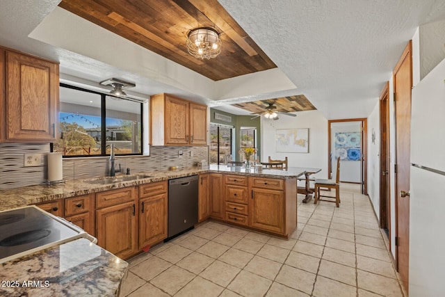 kitchen featuring a sink, a healthy amount of sunlight, freestanding refrigerator, dishwasher, and tasteful backsplash