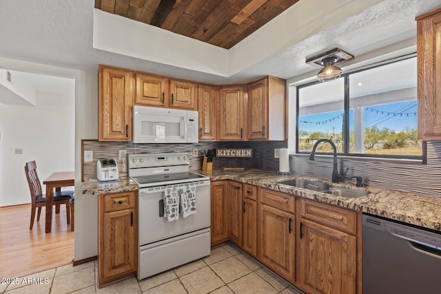 kitchen with tasteful backsplash, white appliances, brown cabinets, and a sink