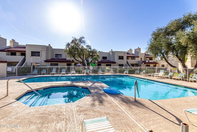 community pool with a community hot tub, a residential view, a patio, and fence