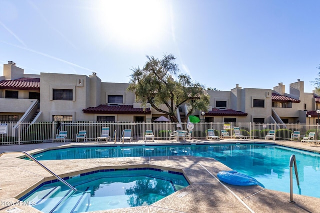 pool with fence and a hot tub