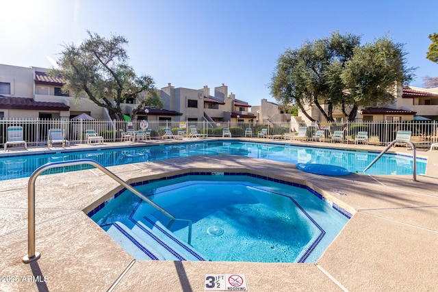 pool with a residential view, a hot tub, a patio, and fence