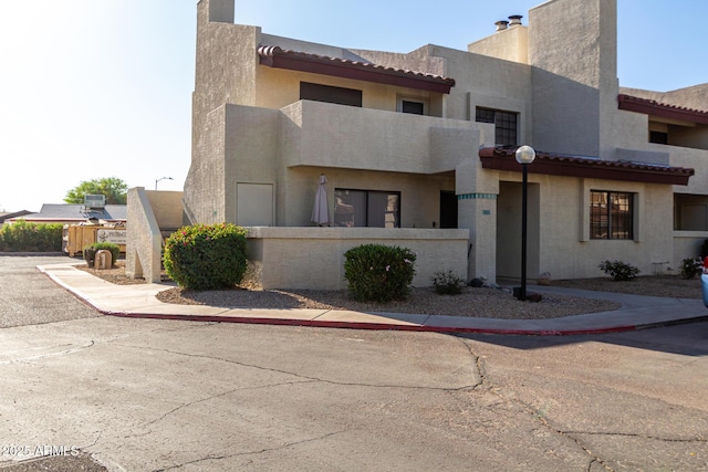 view of front facade with a chimney, stucco siding, and fence private yard