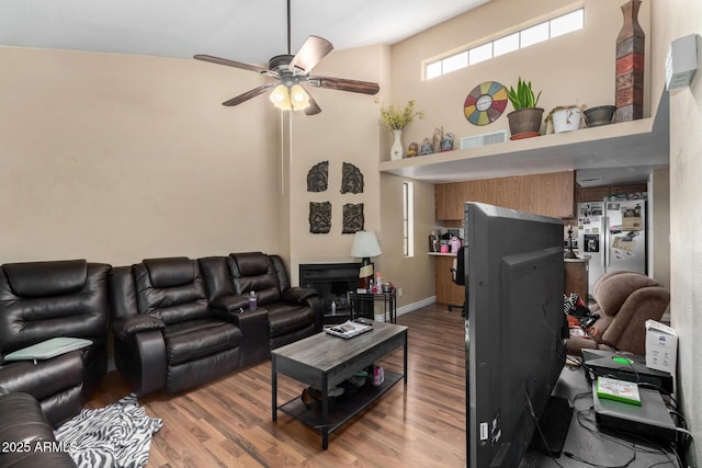 living area with light wood-type flooring, a ceiling fan, and a towering ceiling