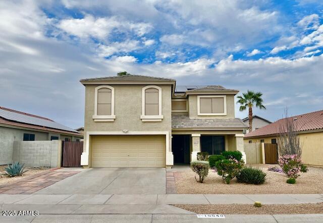 view of front of house featuring a garage, solar panels, fence, concrete driveway, and stucco siding