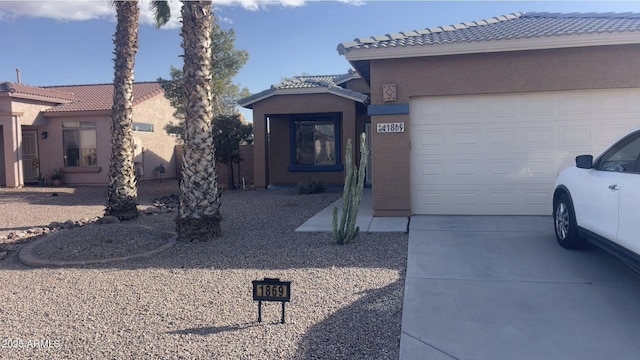 view of front of home featuring a tile roof, driveway, an attached garage, and stucco siding