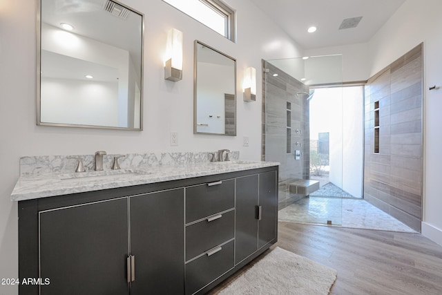 bathroom with vanity, a tile shower, and wood-type flooring