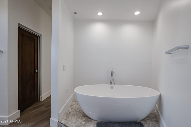 bathroom featuring hardwood / wood-style flooring and a tub to relax in