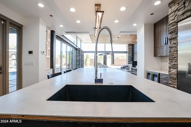 kitchen featuring wine cooler, sink, and a kitchen island with sink