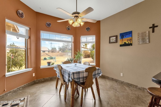 tiled dining space with ceiling fan and lofted ceiling