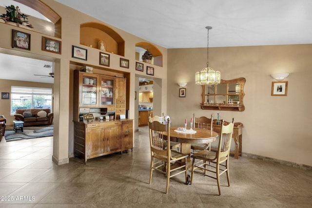 tiled dining room featuring ceiling fan with notable chandelier