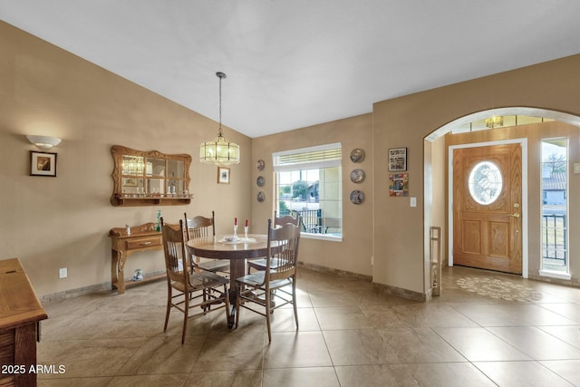 dining room with vaulted ceiling, light tile patterned floors, and a chandelier