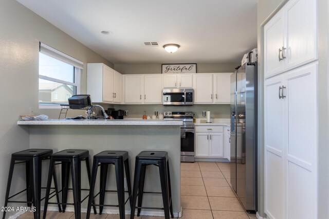 1706 W Coolidge Way, Coolidge, AZ 85128 - kitchen featuring visible vents, a peninsula, a breakfast bar area, white cabinetry, and appliances with stainless steel finishes