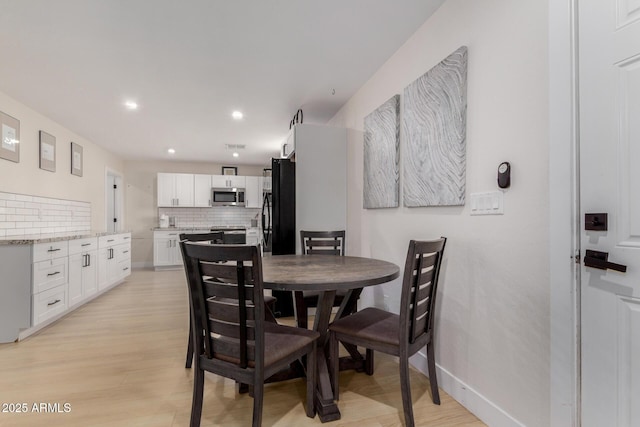 dining area with baseboards, light wood finished floors, and recessed lighting