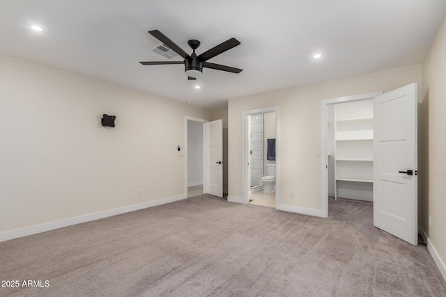unfurnished bedroom featuring a walk in closet, recessed lighting, baseboards, connected bathroom, and light carpet