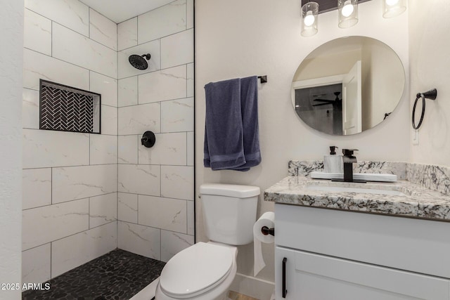 bathroom with toilet, vanity, and tiled shower