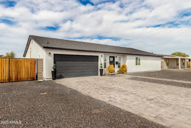 view of front of house featuring stucco siding, fence, an attached garage, driveway, and a gate