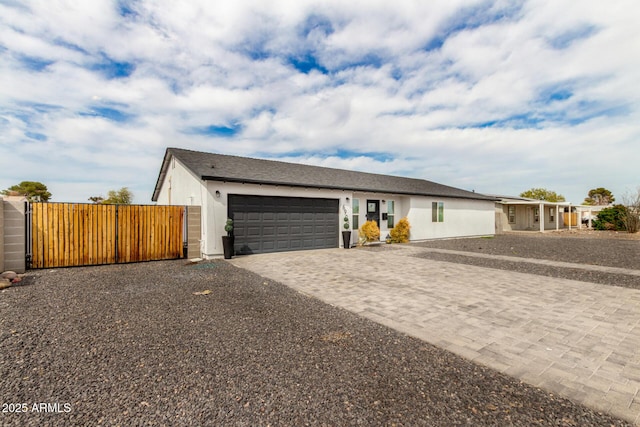 single story home with stucco siding, a gate, a garage, and decorative driveway