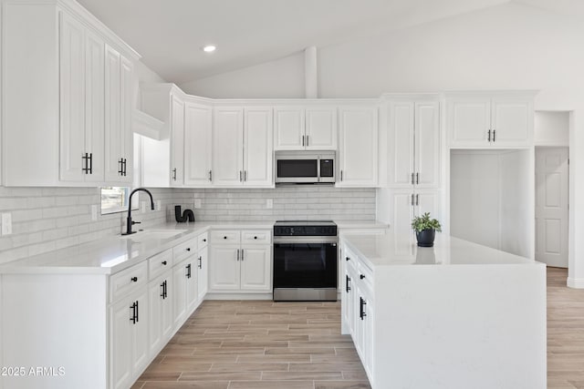 1222 S 365th Ave, Tonopah, AZ 85354 - kitchen with appliances with stainless steel finishes, a sink, vaulted ceiling, backsplash, and white cabinets