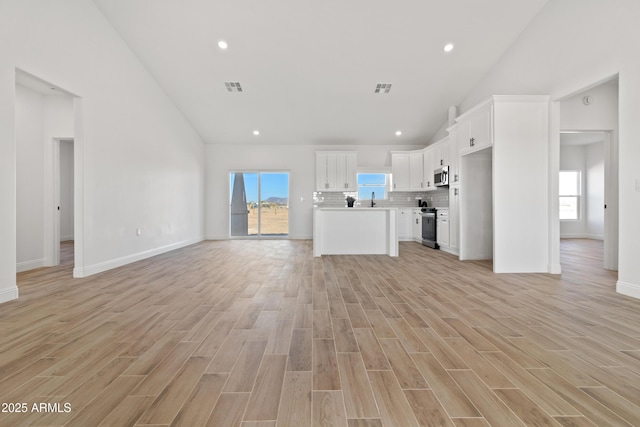1222 S 365th Ave, Tonopah, AZ 85354 - unfurnished living room featuring high vaulted ceiling, healthy amount of natural light, recessed lighting, light wood-style floors, and a sink