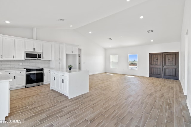1222 S 365th Ave, Tonopah, AZ 85354 - kitchen featuring stainless steel appliances, lofted ceiling, light countertops, backsplash, and white cabinetry
