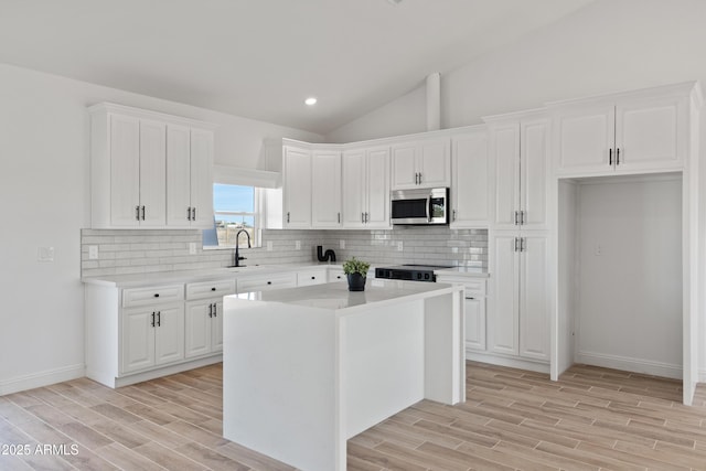 1222 S 365th Ave, Tonopah, AZ 85354 - kitchen with stainless steel microwave, light wood finished floors, backsplash, white cabinets, and lofted ceiling