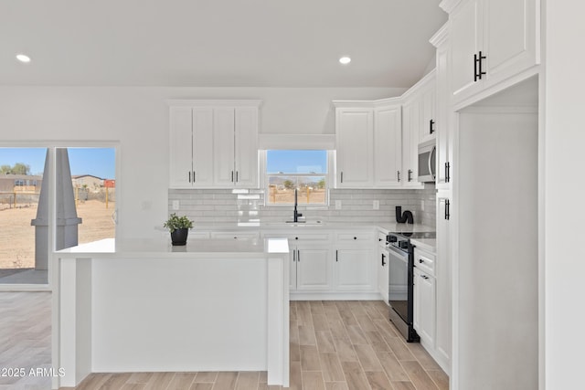 1222 S 365th Ave, Tonopah, AZ 85354 - kitchen featuring black / electric stove, stainless steel microwave, light countertops, a sink, and white cabinetry