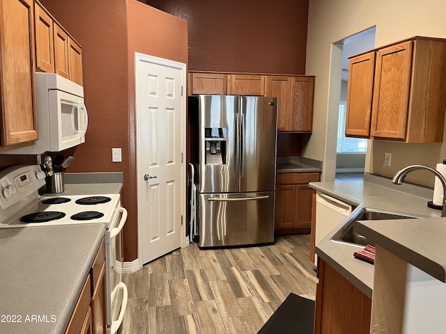 kitchen featuring sink, white appliances, and light wood-type flooring