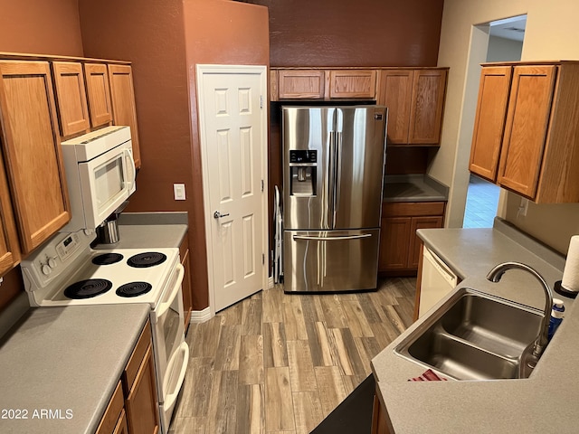 kitchen with sink, white appliances, and light hardwood / wood-style flooring