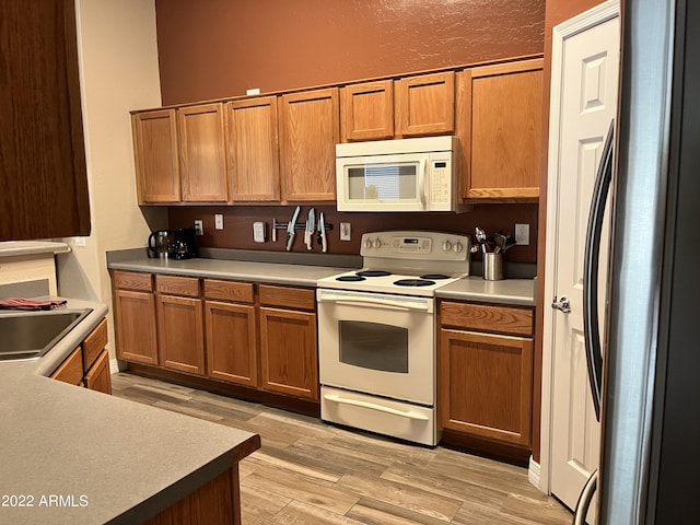 kitchen with white appliances, sink, and light wood-type flooring