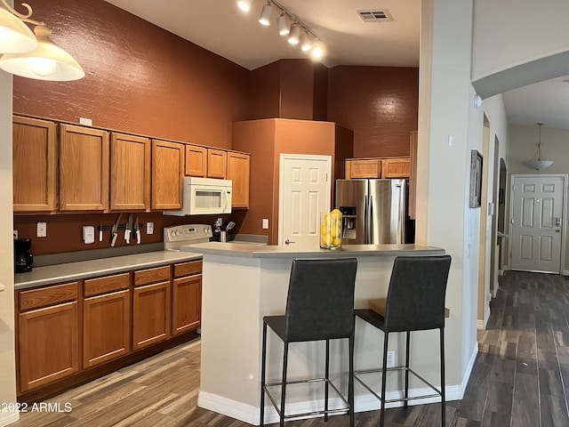 kitchen with hardwood / wood-style flooring, a center island, stainless steel fridge, and a kitchen breakfast bar