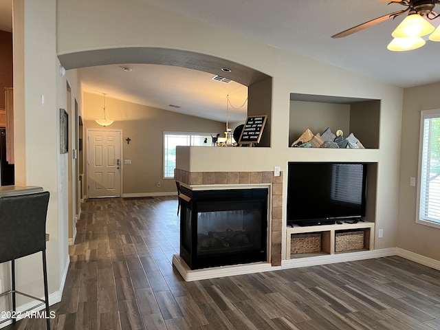 unfurnished living room with vaulted ceiling, a healthy amount of sunlight, a multi sided fireplace, and dark hardwood / wood-style floors