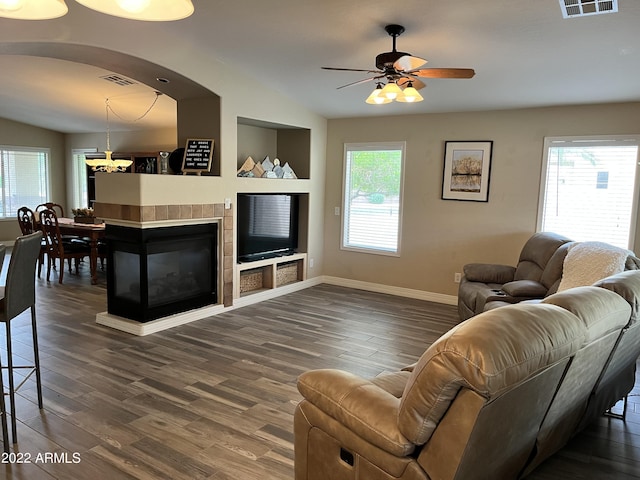 living room with dark hardwood / wood-style flooring, ceiling fan with notable chandelier, lofted ceiling, and a tile fireplace