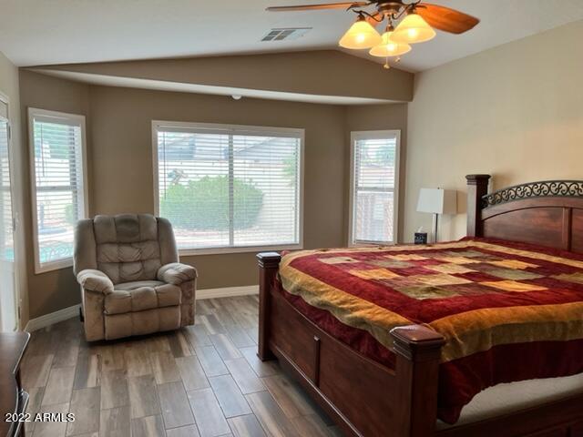 bedroom with hardwood / wood-style flooring, ceiling fan, lofted ceiling, and multiple windows