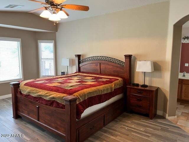 bedroom with vaulted ceiling, dark hardwood / wood-style floors, ensuite bathroom, and ceiling fan