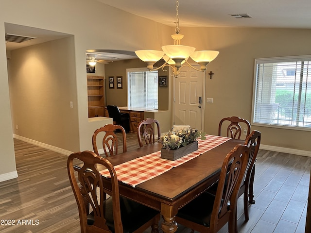 dining room featuring lofted ceiling, hardwood / wood-style flooring, and ceiling fan with notable chandelier