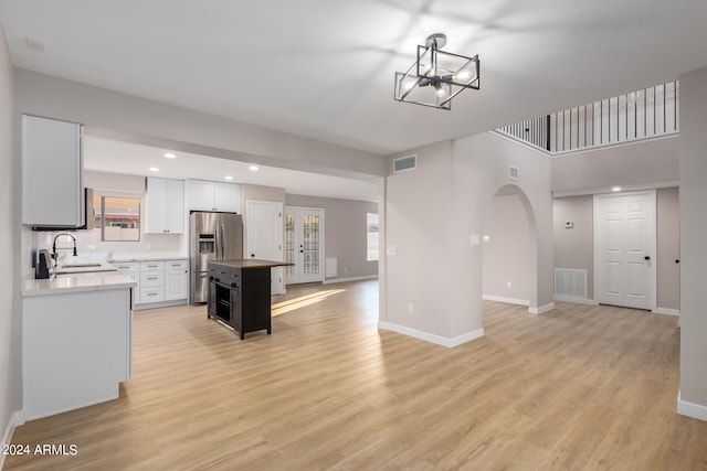 kitchen featuring light hardwood / wood-style floors, a kitchen island, stainless steel fridge, and sink