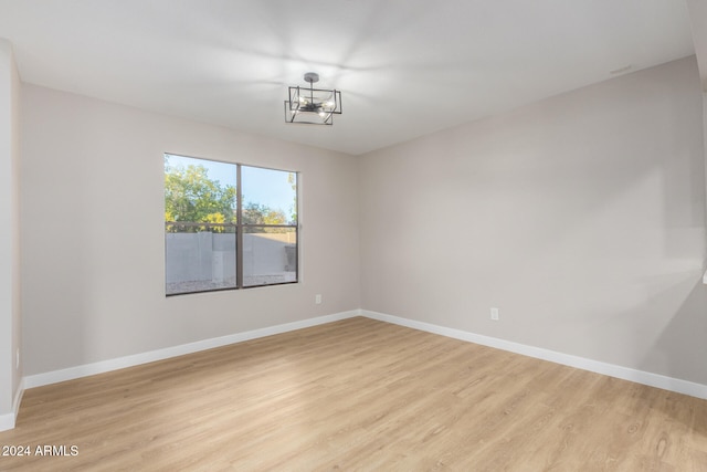 empty room with light hardwood / wood-style floors and a notable chandelier