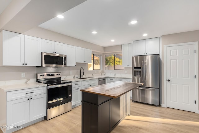 kitchen featuring butcher block counters, white cabinetry, stainless steel appliances, and light hardwood / wood-style flooring