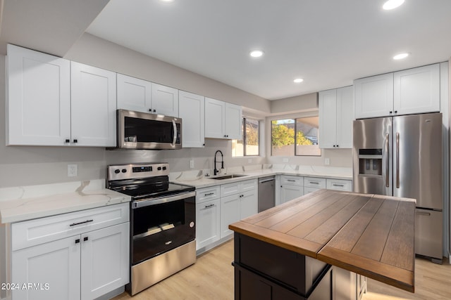 kitchen featuring light hardwood / wood-style flooring, sink, stainless steel appliances, light stone countertops, and white cabinetry