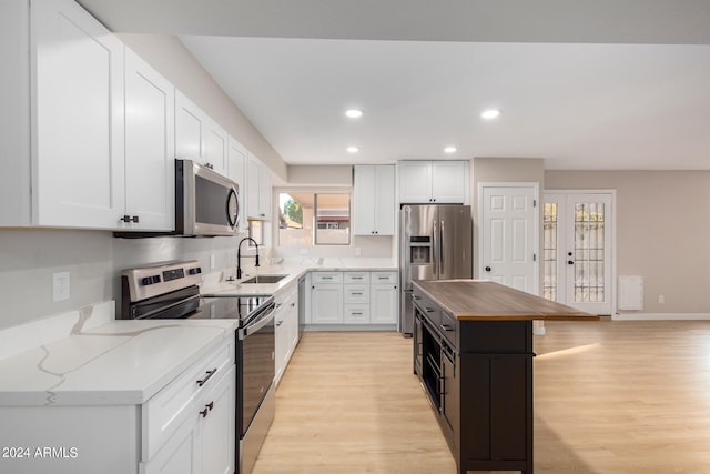 kitchen with white cabinets, stainless steel appliances, light wood-type flooring, and sink