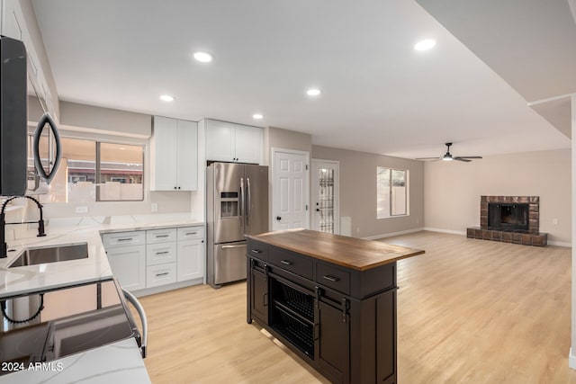 kitchen with light hardwood / wood-style flooring, white cabinets, stainless steel fridge with ice dispenser, and sink