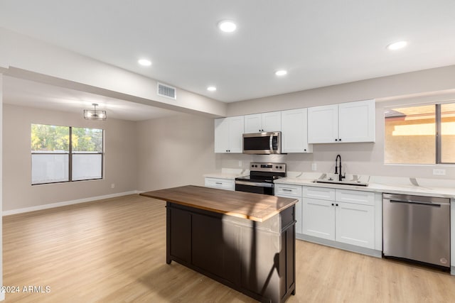 kitchen featuring butcher block countertops, appliances with stainless steel finishes, sink, and white cabinetry