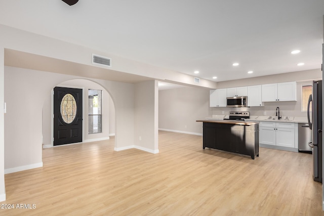 kitchen featuring appliances with stainless steel finishes, light wood-type flooring, sink, and white cabinets