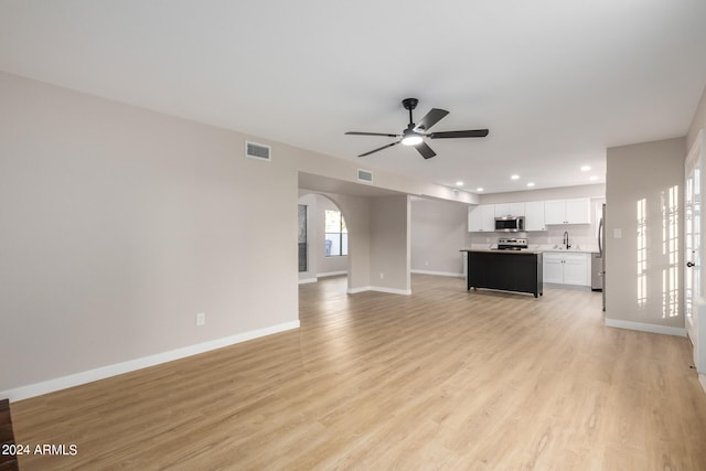 unfurnished living room with light hardwood / wood-style floors, sink, and ceiling fan