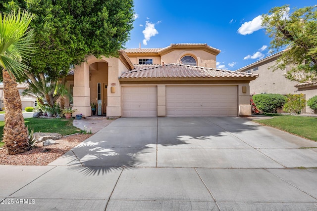 mediterranean / spanish-style home with stucco siding, an attached garage, concrete driveway, and a tile roof