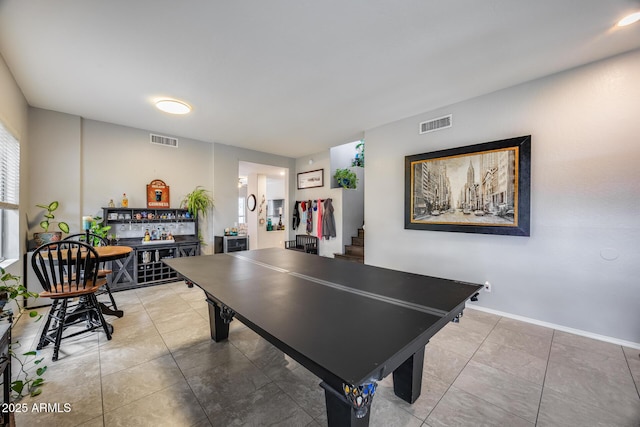 rec room featuring a bar, light tile patterned flooring, and baseboards