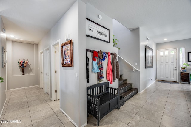 hallway with light tile patterned flooring, baseboards, stairs, and recessed lighting