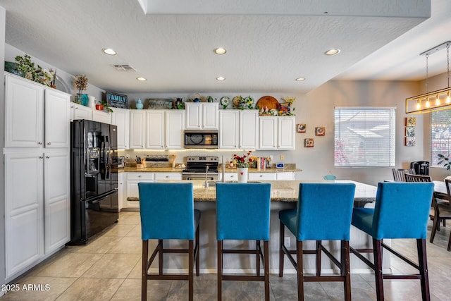 kitchen with appliances with stainless steel finishes, recessed lighting, white cabinetry, a kitchen breakfast bar, and a center island with sink