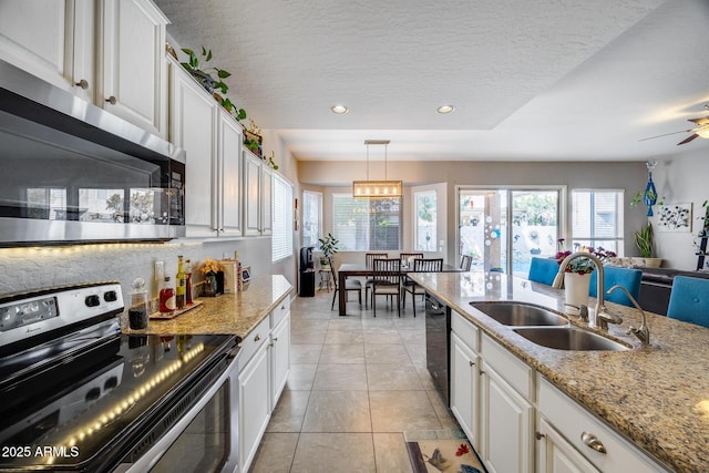 kitchen featuring stainless steel appliances, a sink, plenty of natural light, white cabinetry, and recessed lighting